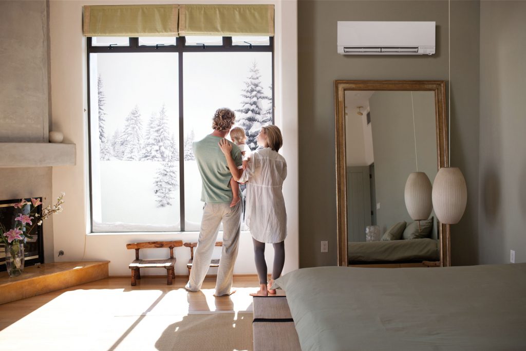 Family at a window with a ductless Mitsubishi unit on the wall.